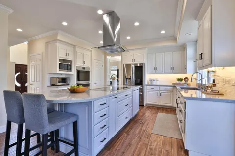 a kitchen with stainless steel appliances a sink a stove a refrigerator cabinets and a center island