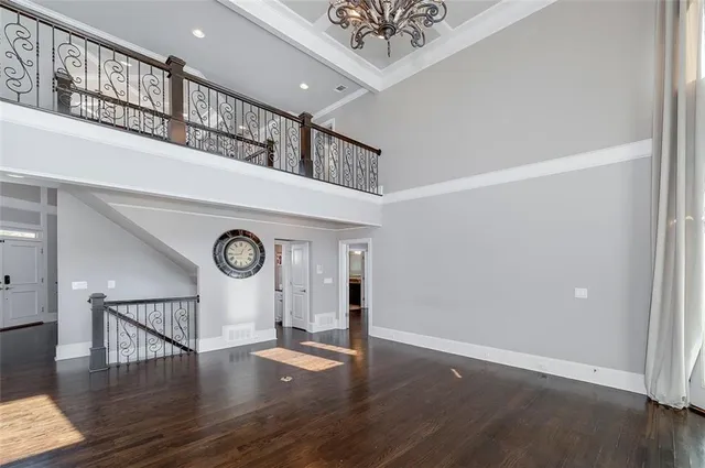 a view of a room with wooden floor chandelier and windows