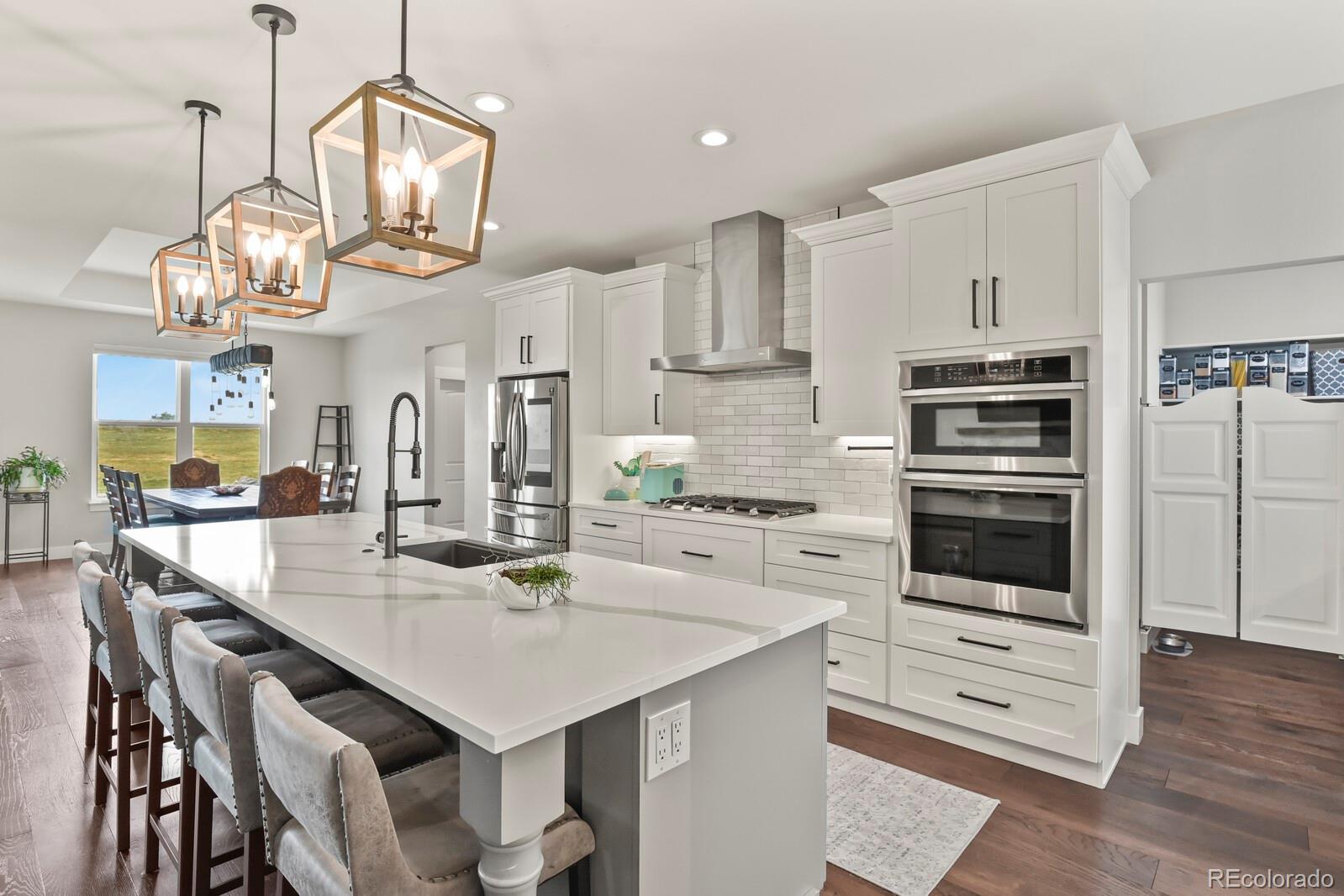 11617 Harpenden Court Fort Lupton, CO 80621 - Photo 3 of 50 a kitchen with stainless steel appliances kitchen island granite countertop a table chairs and a stove