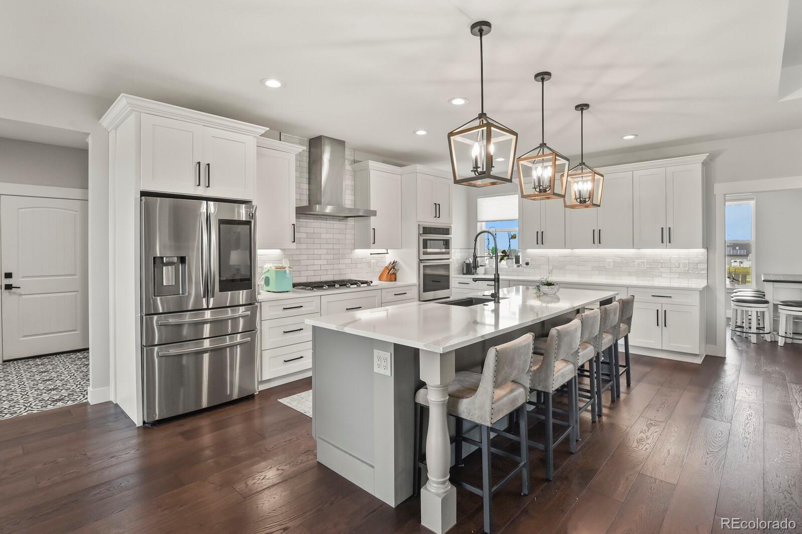 11617 Harpenden Court Fort Lupton, CO 80621 - Photo 6 of 50 a kitchen with stainless steel appliances kitchen island granite countertop a table chairs refrigerator and cabinets