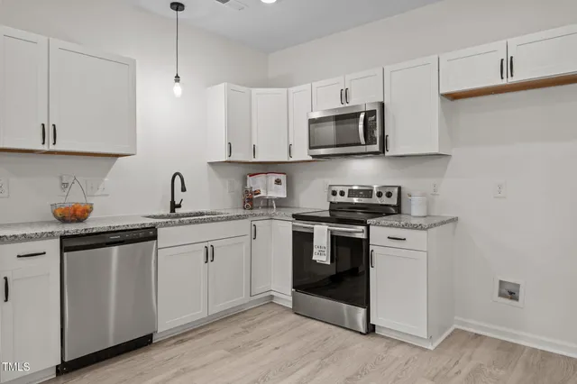 a kitchen with stainless steel appliances granite countertop a sink a stove a microwave and wooden cabinets