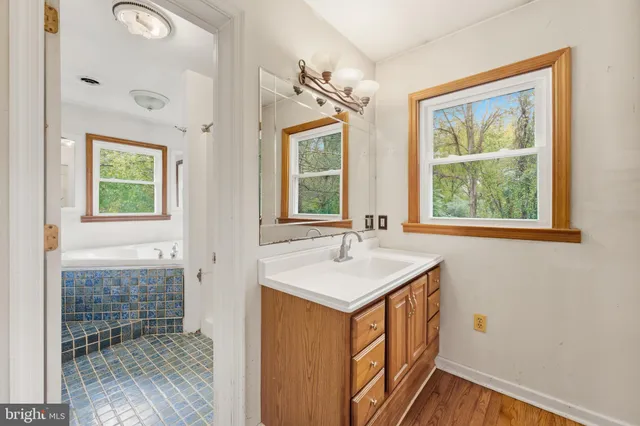 a bathroom with a sink a mirror and next to a window