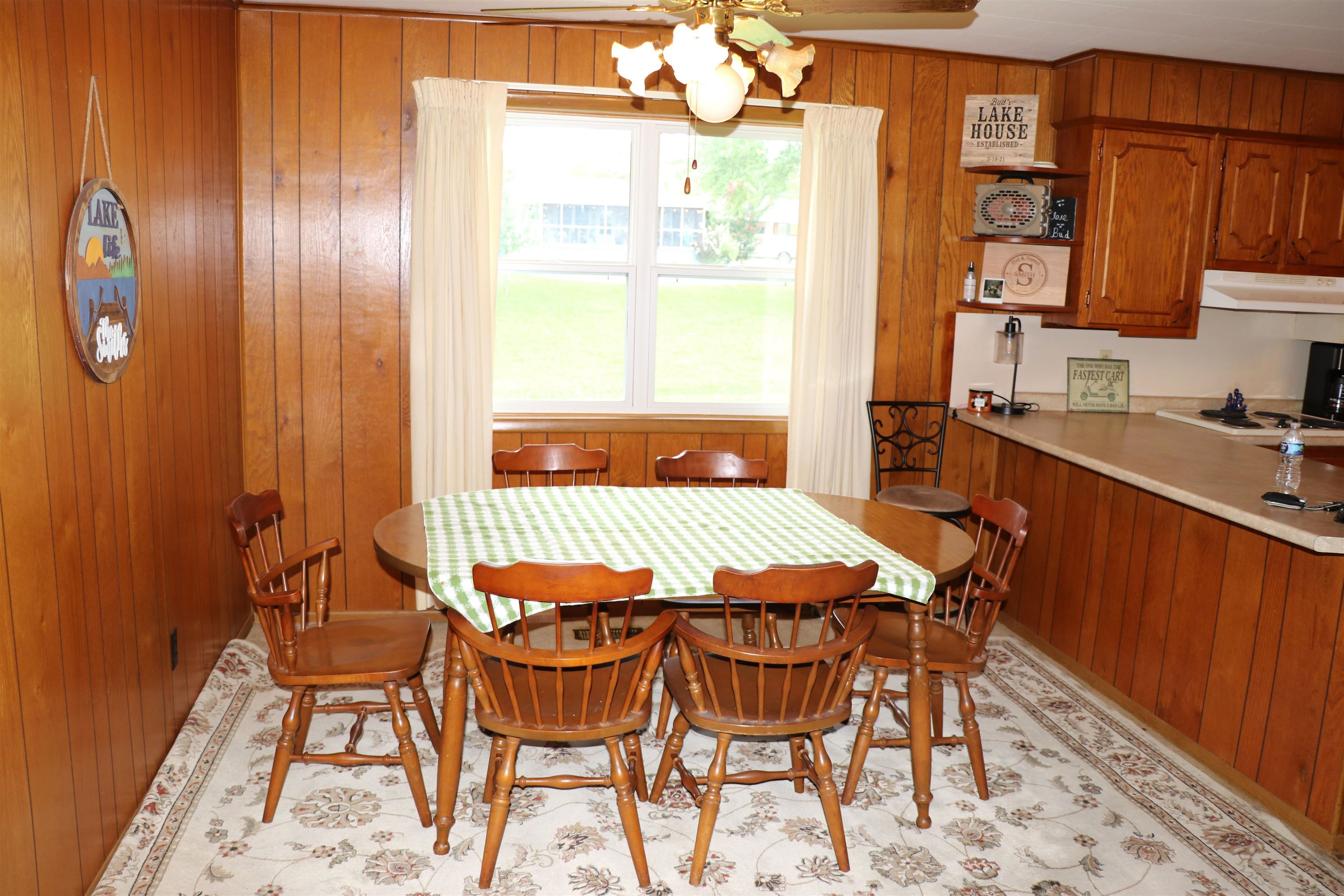160 Patrick Drive Springville, TN 38256 - Photo 5 of 34 Dining area featuring wood-finish wall paneling, a large window with white trim, and a ceiling fan with integrated lighting