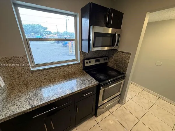 a kitchen with granite countertop a stove a microwave a sink and cabinets