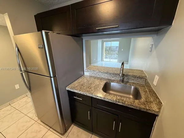 a kitchen with granite countertop a sink and a refrigerator