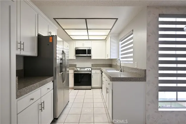 a kitchen with stainless steel appliances granite countertop a refrigerator a sink dishwasher a stove and a microwave oven