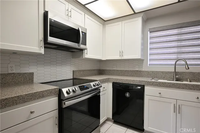 a kitchen with stainless steel appliances granite countertop white cabinets granite counter tops and a wooden floors