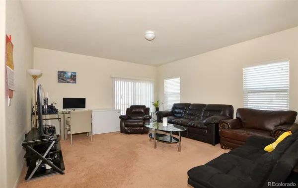 a living room with furniture a computer on the desk and a flat screen tv