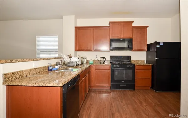 a kitchen with granite countertop a refrigerator stove top oven and sink