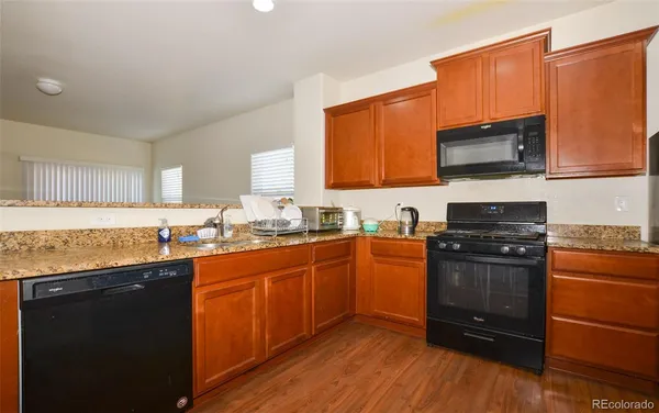 a kitchen with granite countertop a stove top oven sink and cabinets