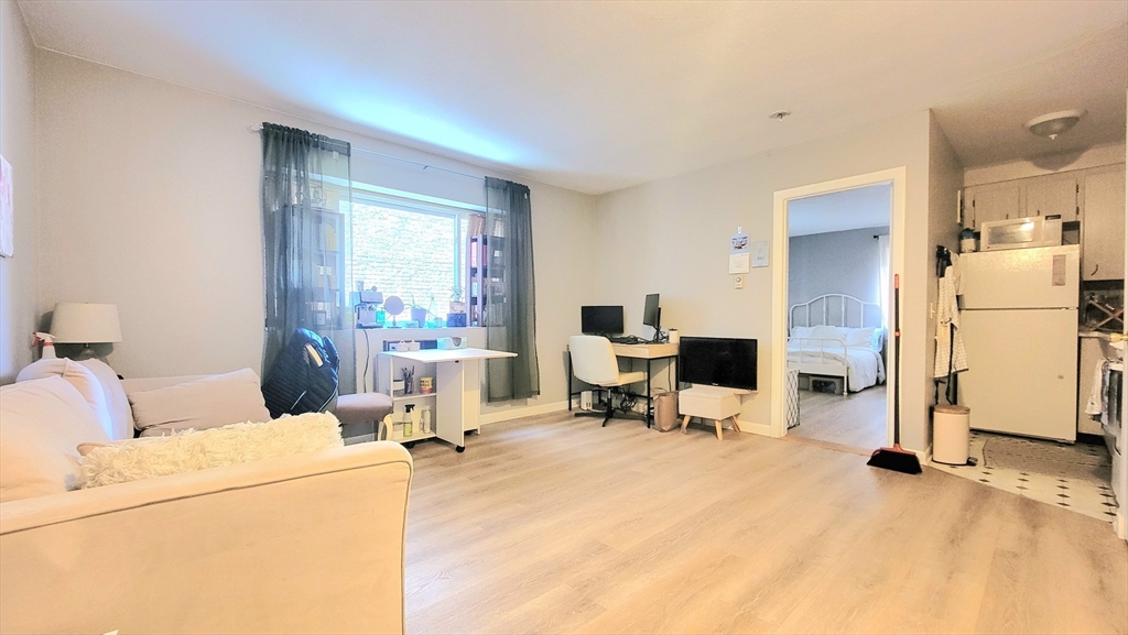a living room with furniture a dining table and a refrigerator