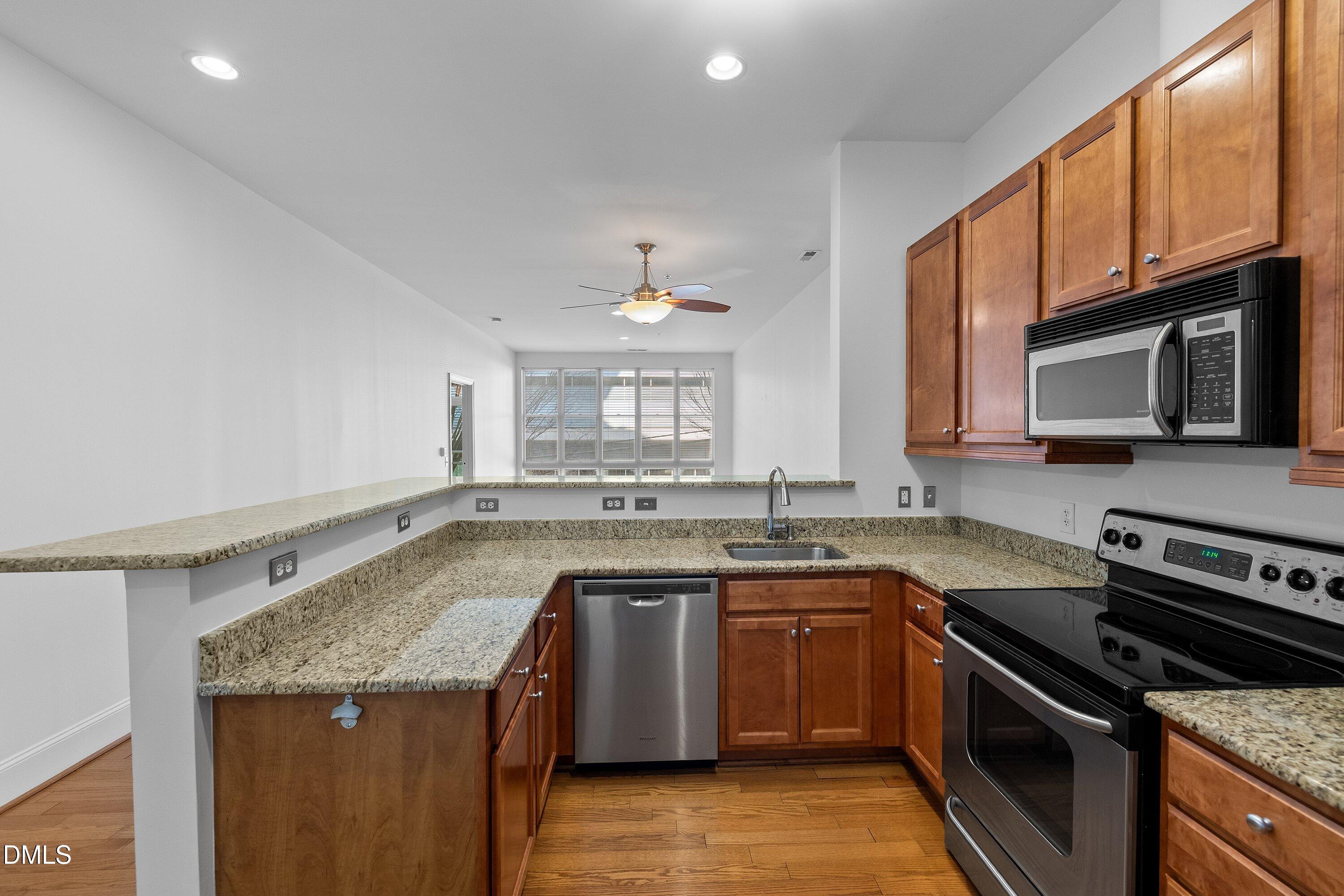 317 West Morgan Street, Unit 215 Raleigh, NC 27601 - Photo 7 of 38 a kitchen with granite countertop a sink stove and microwave