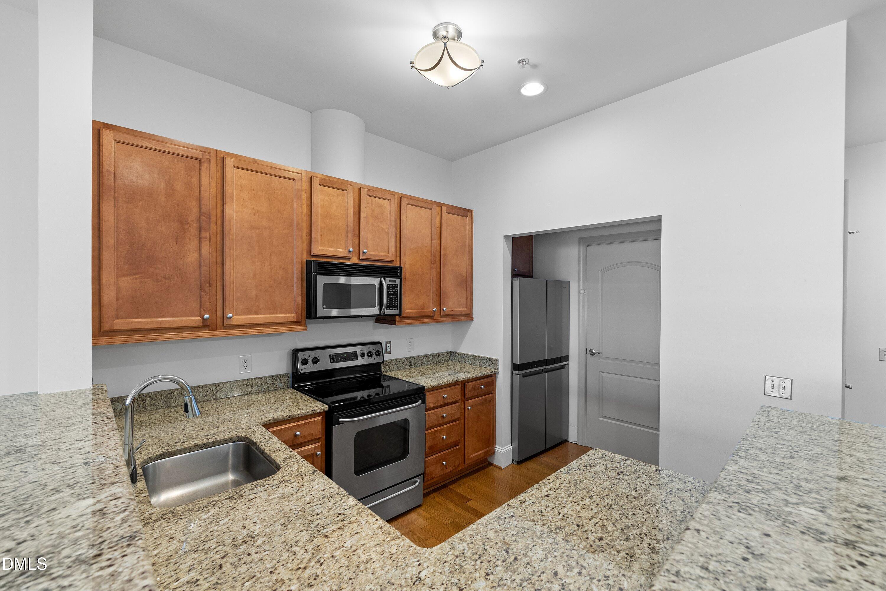 317 West Morgan Street, Unit 215 Raleigh, NC 27601 - Photo 8 of 38 a kitchen with granite countertop a refrigerator and a stove top oven