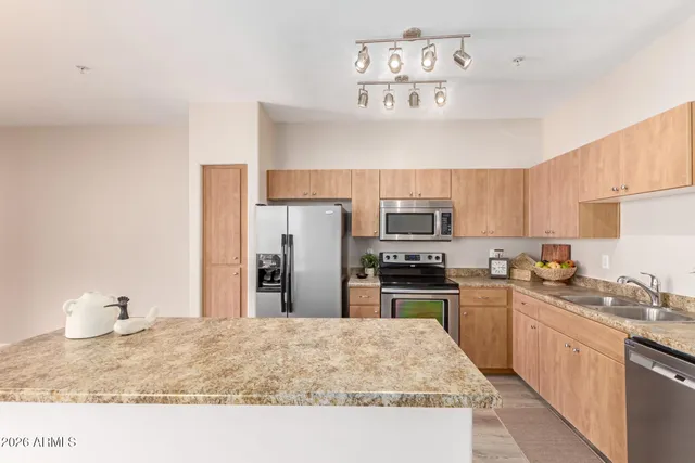 a kitchen with stainless steel appliances granite countertop a sink refrigerator stove and microwave