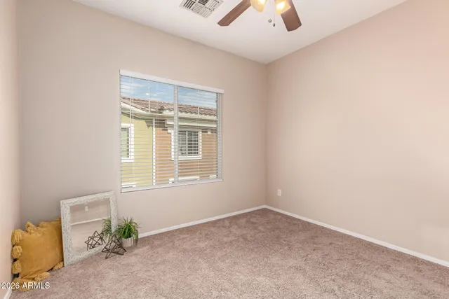 an empty room with a window and a chandelier fan