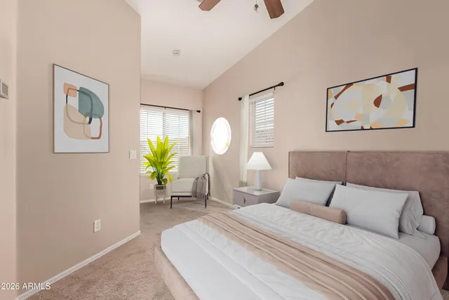a bedroom with a bed lamp and paintings on the wall