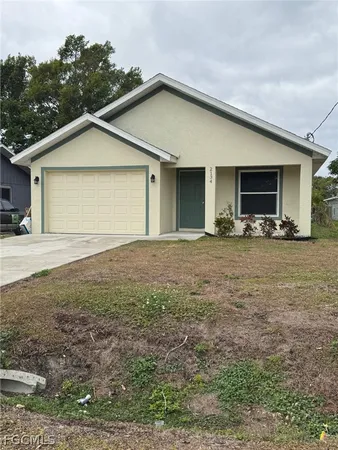 a view of a house with backyard and trees in the background