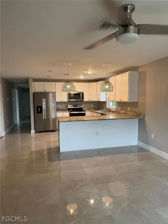 a large kitchen with stainless steel appliances a sink a stove and cabinets