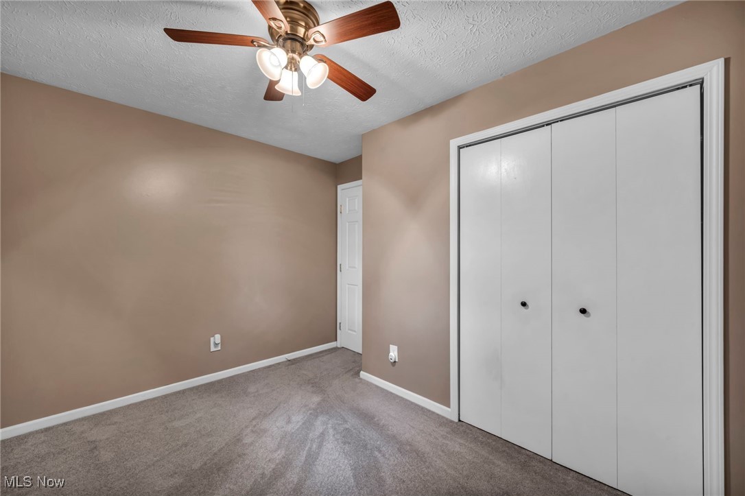 47655 Cooper Foster Park Road Amherst, OH 44001 - Photo 17 of 49 Unfurnished bedroom with a textured ceiling, carpet flooring, a closet, and ceiling fan