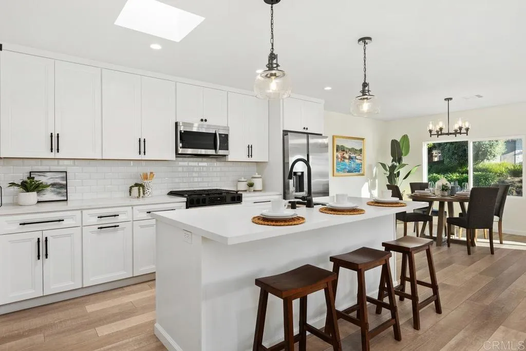 7144 Santa Rosa, Unit 86 Carlsbad, CA 92011 - Photo 8 of 41 a kitchen with a dining table chairs and refrigerator