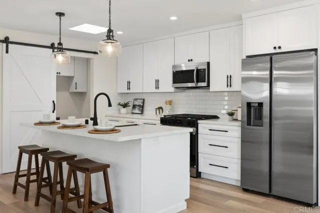 a kitchen with stainless steel appliances kitchen island a table chairs refrigerator and microwave