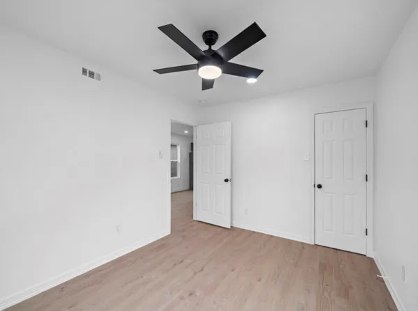 an empty room with ceiling fan and wooden floor