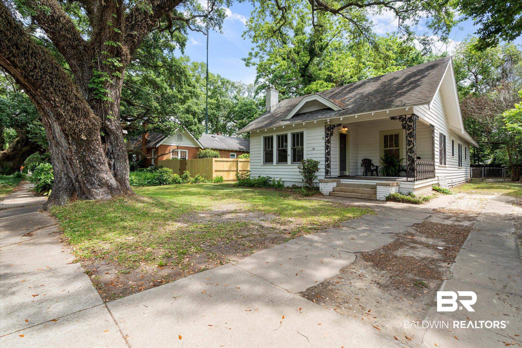 121 Westwood Street Mobile, AL 36606 - Photo 19 of 20 Bungalow-style house featuring a chimney, fence, driveway, covered porch, and roof with shingles