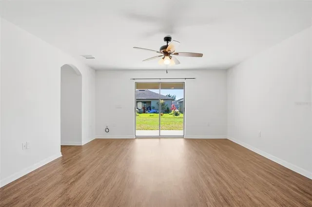 a view of an empty room with a window and wooden floor