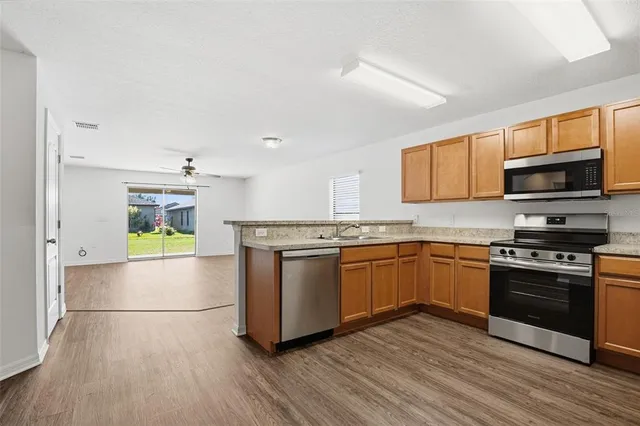 a kitchen with stainless steel appliances granite countertop a stove a sink and a microwave