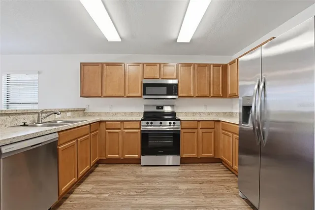 a kitchen with granite countertop a sink stove and refrigerator