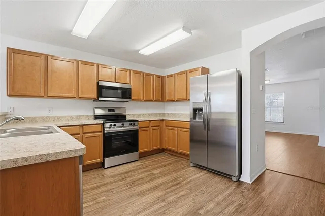 a kitchen with granite countertop a refrigerator a sink a stove top oven and cabinetry