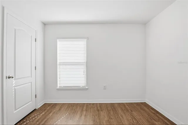 a view of a room that has wooden floor and a window