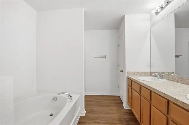 a spacious bathroom with a granite countertop sink and a bathtub