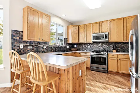 a kitchen with stainless steel appliances a stove a sink a microwave a refrigerator and cabinets