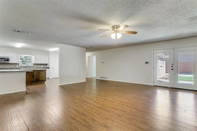 a view of an empty room with a kitchen and wooden floor