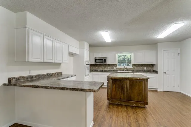 a kitchen with stainless steel appliances granite countertop a stove a sink and a microwave