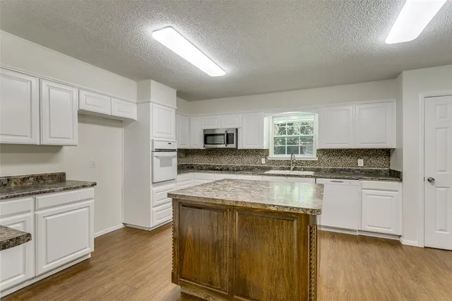 a kitchen with stainless steel appliances granite countertop wooden cabinets and a stove top oven