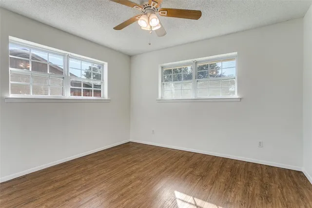a view of empty room with wooden floor and fan