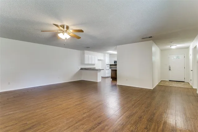 a view of empty room with wooden floor and ceiling fan