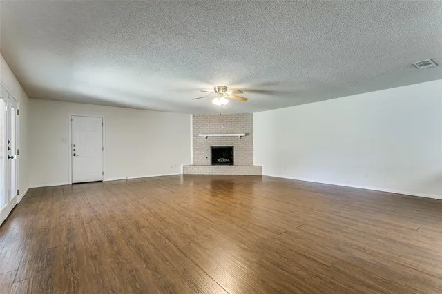 a view of an empty room with wooden floor and a fireplace