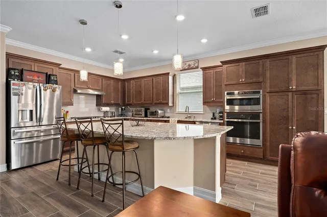 a kitchen with stainless steel appliances granite countertop sink stove refrigerator and cabinets