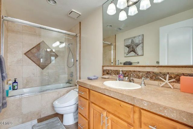 a bathroom with a granite countertop sink vanity mirror bathtub shower and toilet