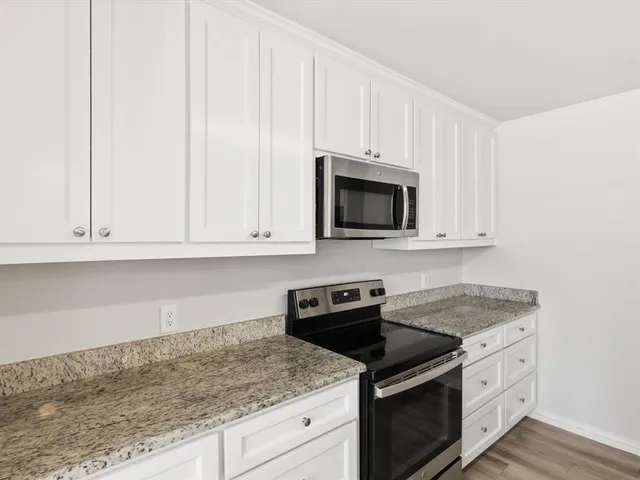a kitchen with granite countertop white cabinets and stainless steel appliances
