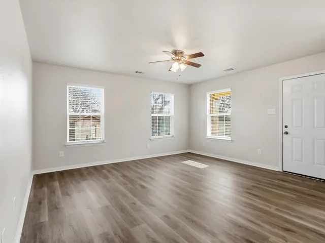 a view of an empty room with a window and wooden floor