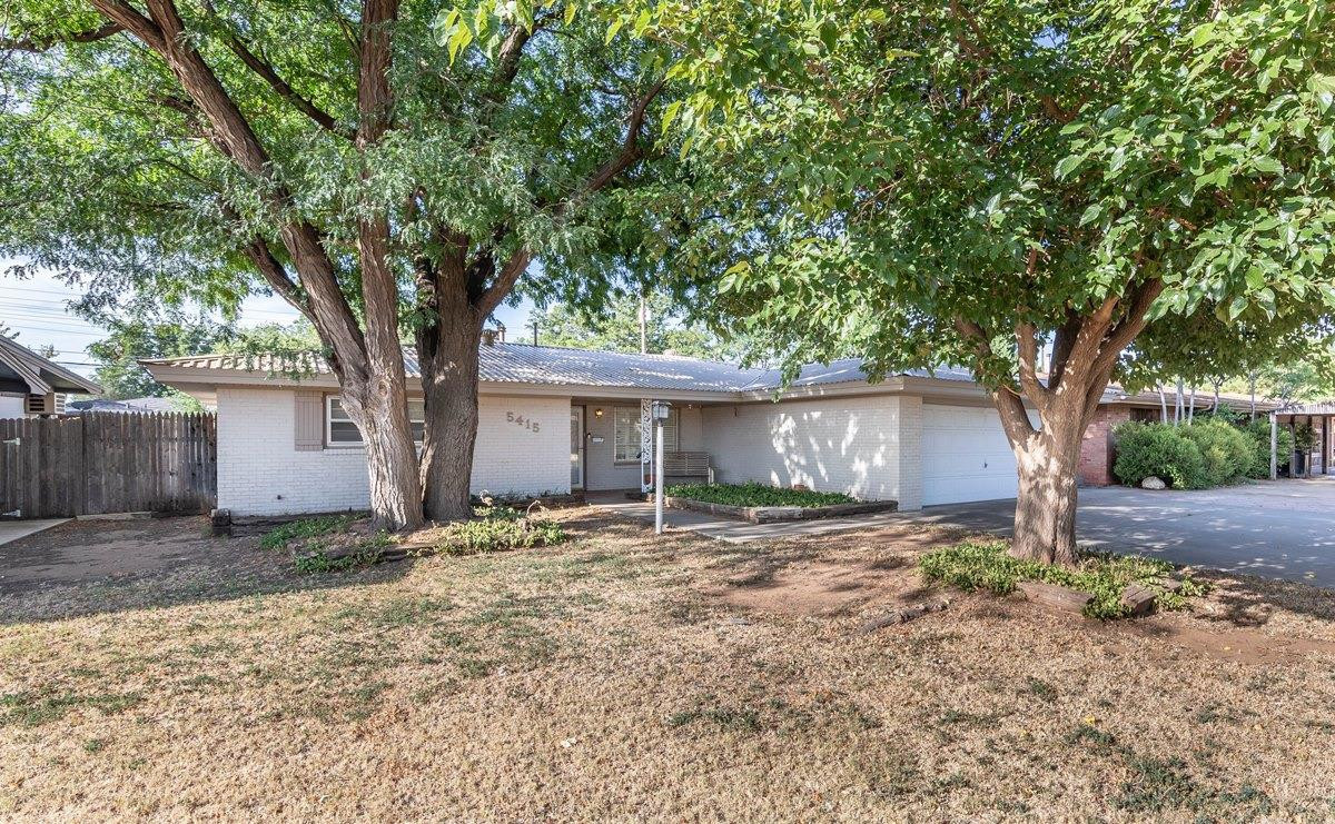 a large tree in front of a white house