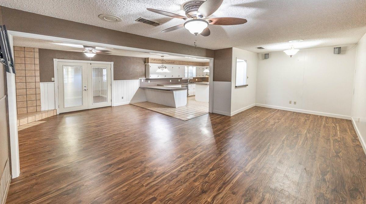 5415 8th Street Lubbock, TX 79416 - Photo 17 of 27 a view of an empty room with wooden floor and a kitchen