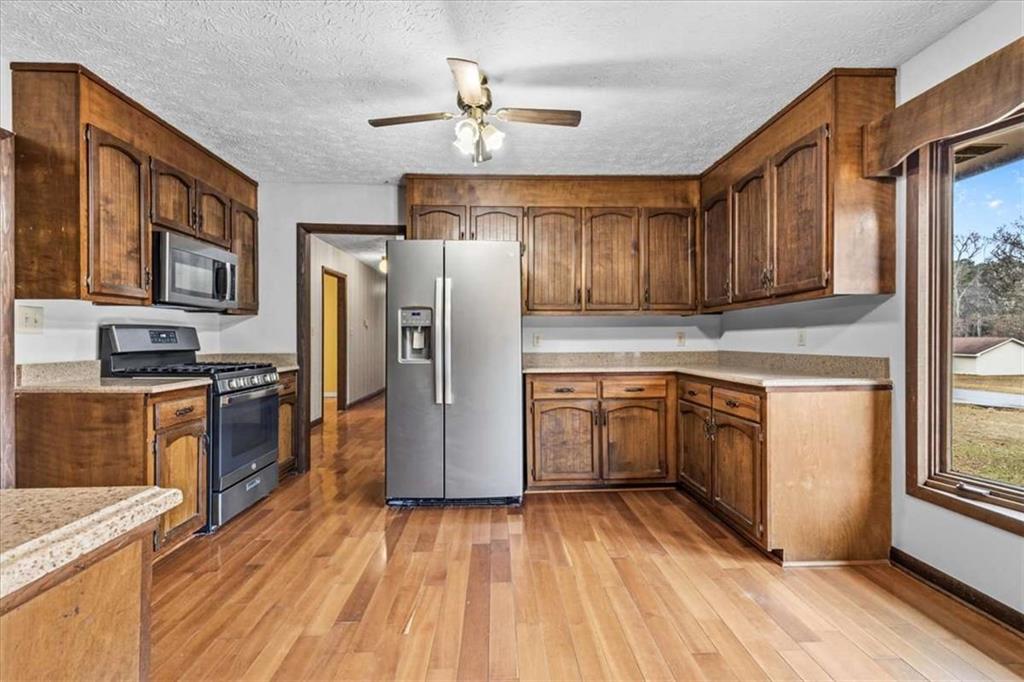 202 Ridgewood Road Cedartown, GA 30125 - Photo 15 of 39 a kitchen with granite countertop a refrigerator oven a sink dishwasher and wooden cabinets with wooden floor