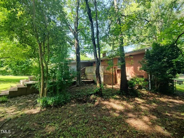 a view of house with a big yard and potted plants