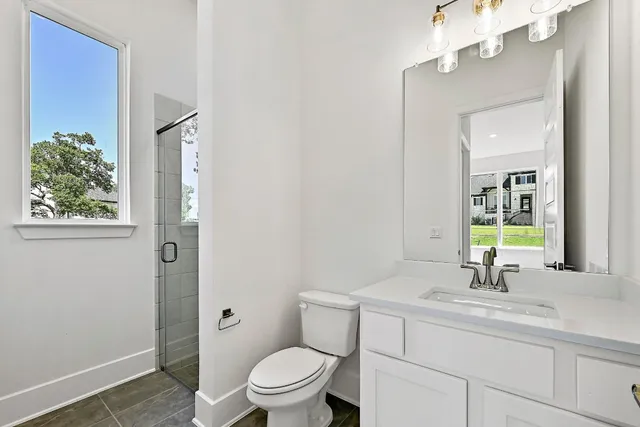 a bathroom with a toilet a sink a mirror a vanity and window