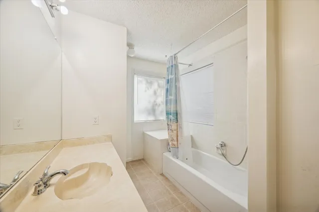 a bathroom with a granite countertop sink a mirror and a bathtub